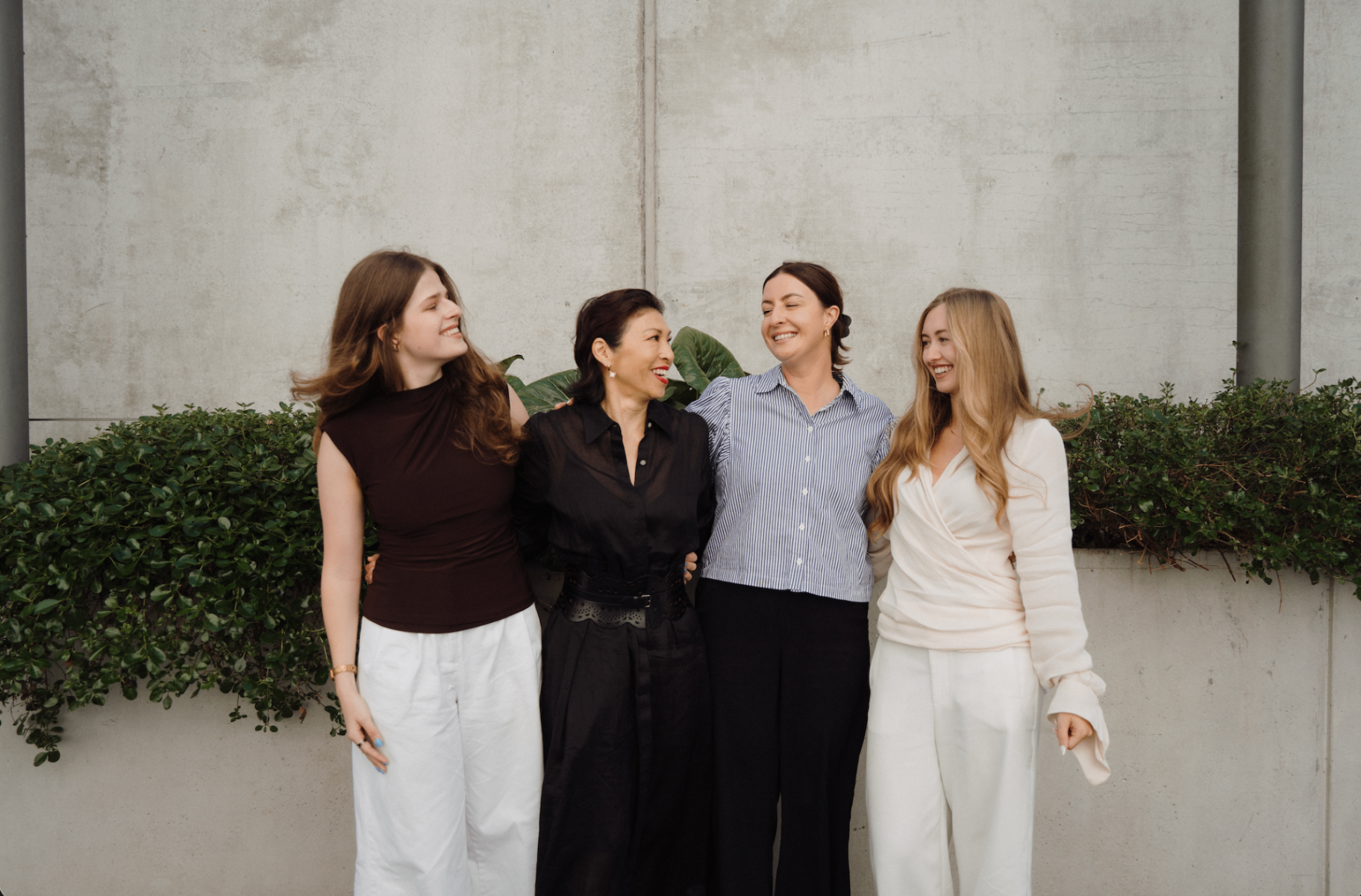 The re:ampd team - four women smiling together against a concrete wall