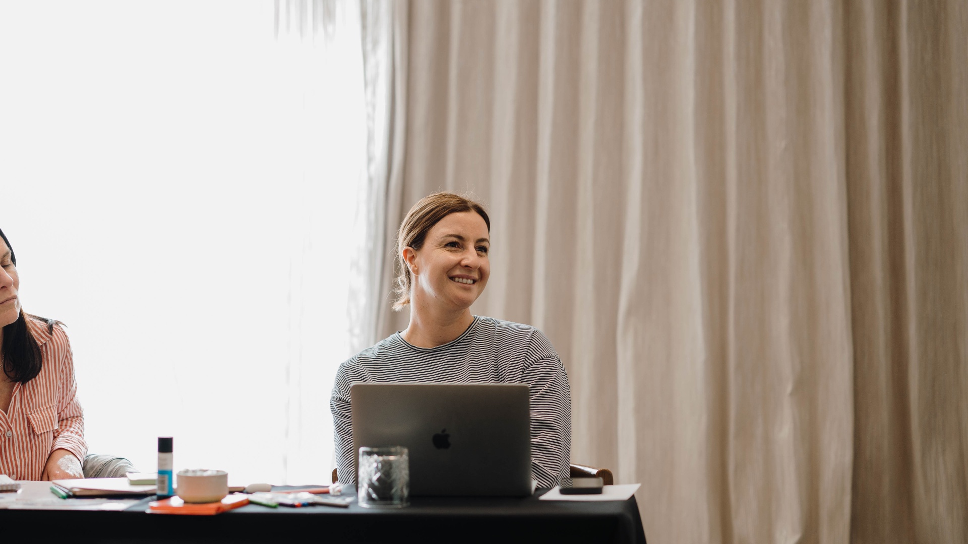 A woman smiling at her laptop during a re:ampd AI masterclass